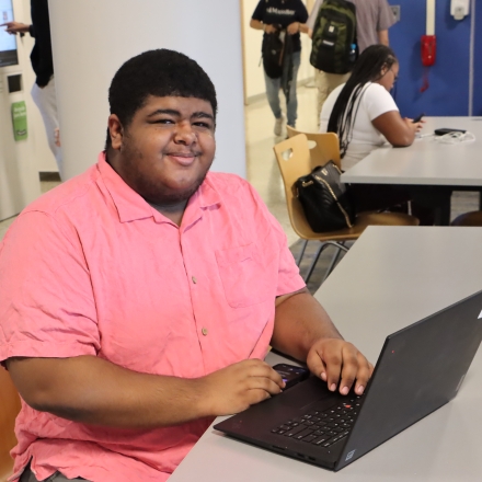 Smiling student at laptop in cafeteria